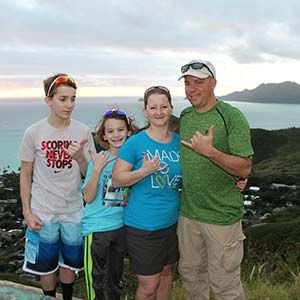 Family posing for a photo at a scenic coastal lookout on O'ahu