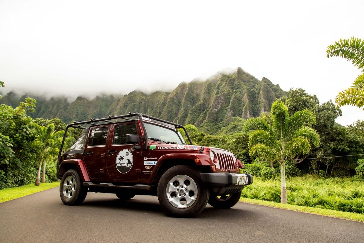 Jeep parked in front of the jagged green ridges of Kualoa on O'ahu